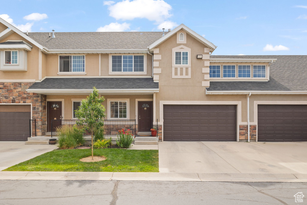 Townhome / multi-family property with stone siding, stucco siding, and driveway