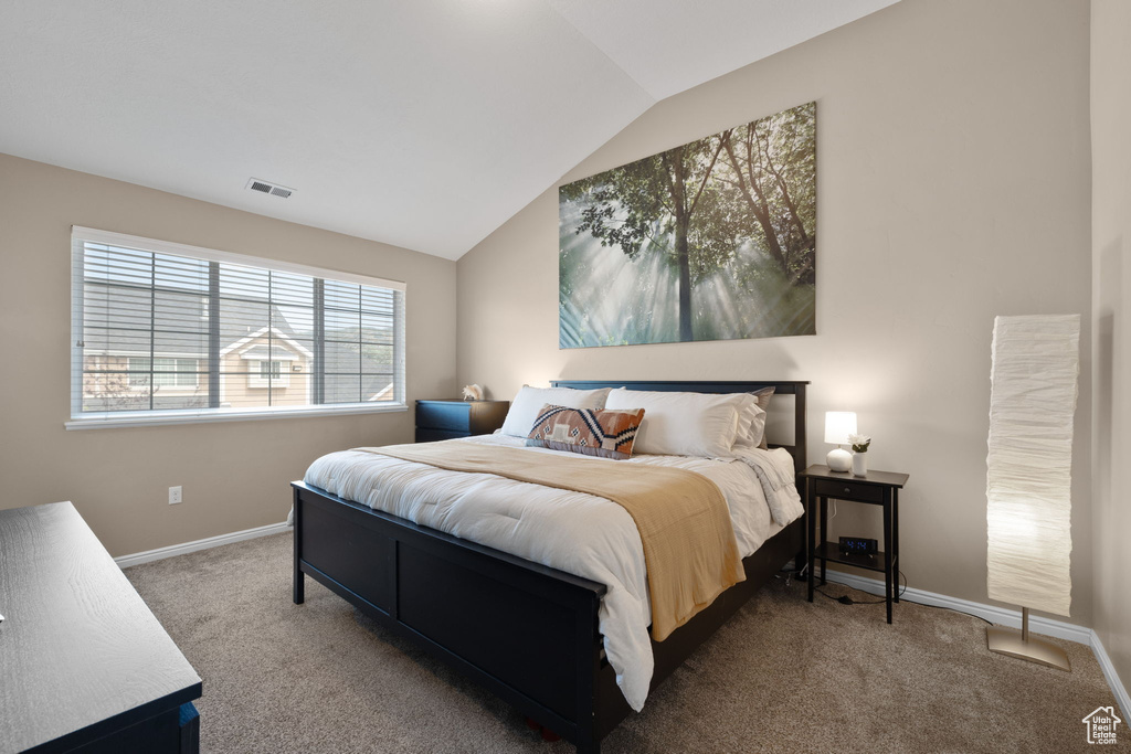 Carpeted bedroom with baseboards and vaulted ceiling