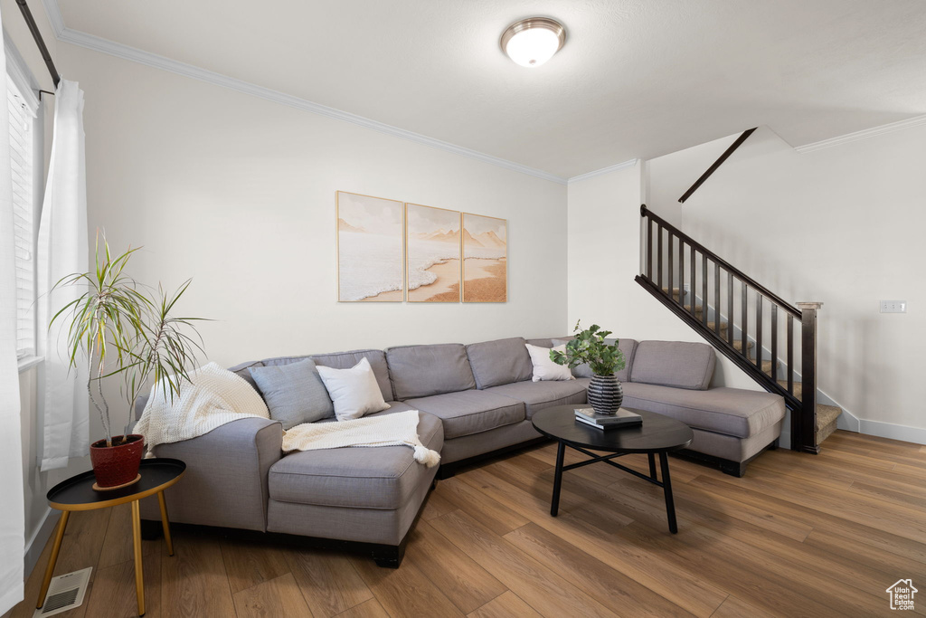 Living room featuring ornamental molding, stairs, and wood finished floors