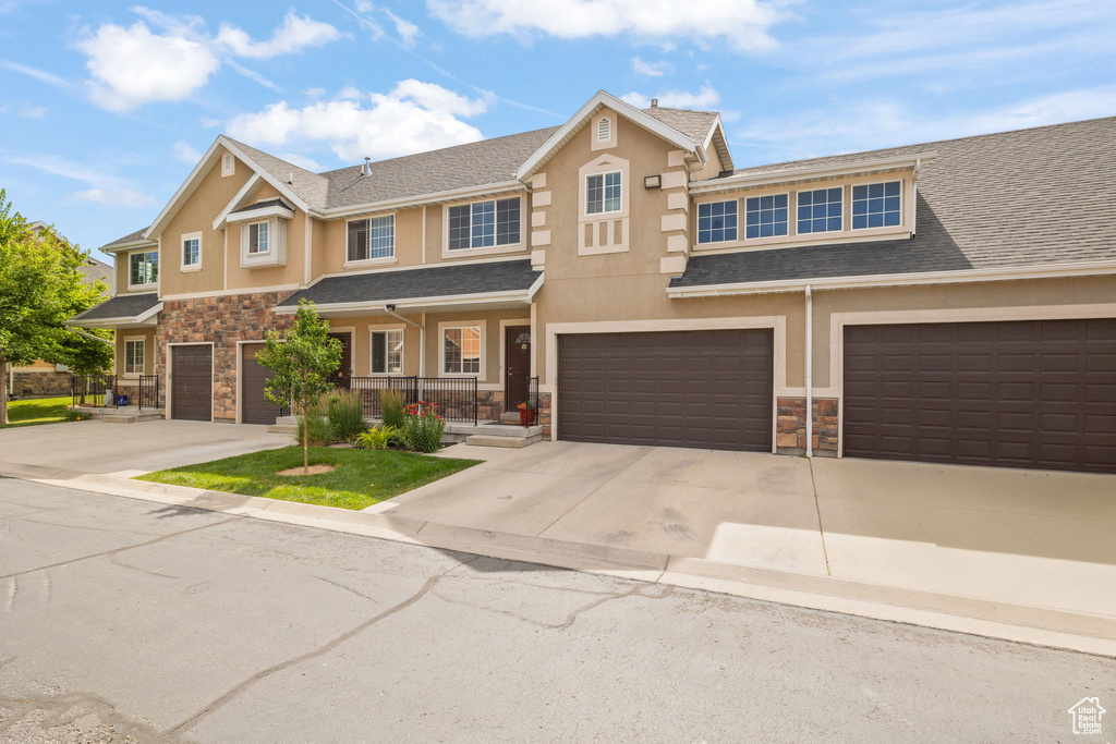 View of property featuring stone siding, driveway, and an attached garage