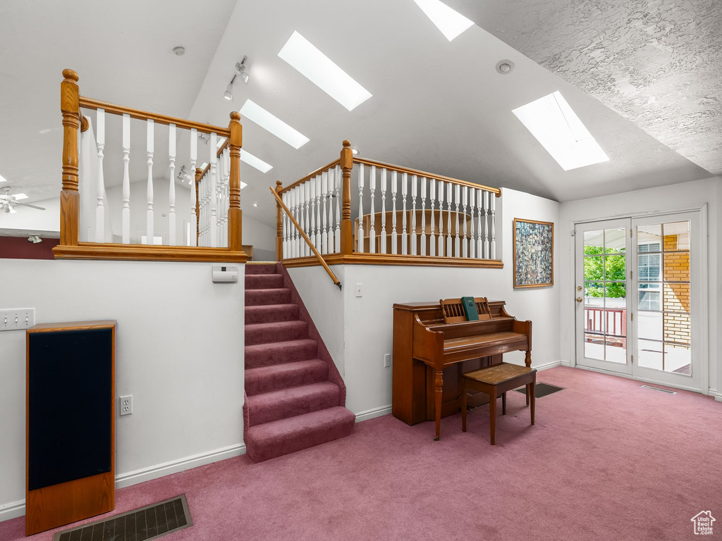 Stairway featuring a skylight, vaulted ceiling, and carpet floors