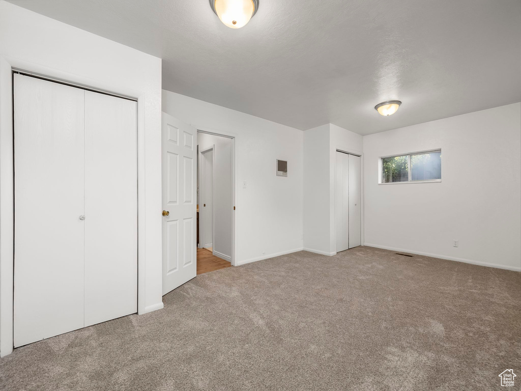 Unfurnished bedroom featuring carpet and two closets