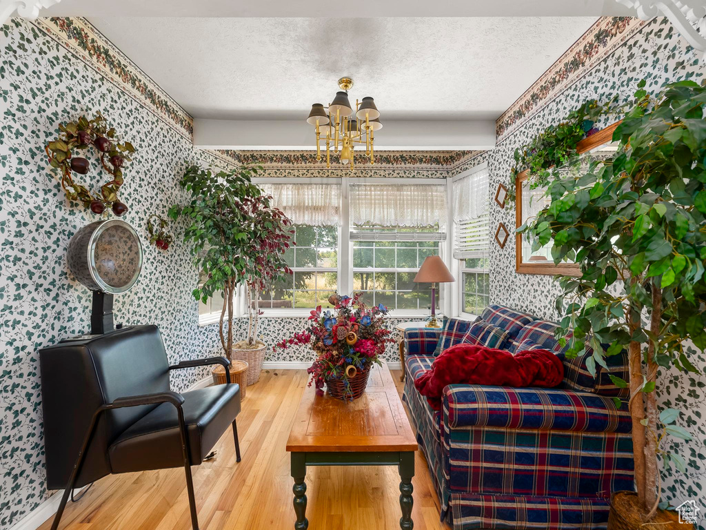 Living area featuring wallpapered walls, a chandelier, wood finished floors, and a textured ceiling
