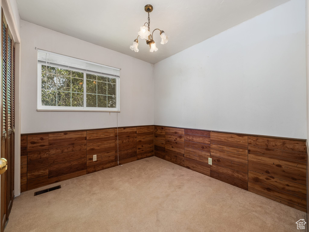 Empty room featuring a chandelier and carpet flooring