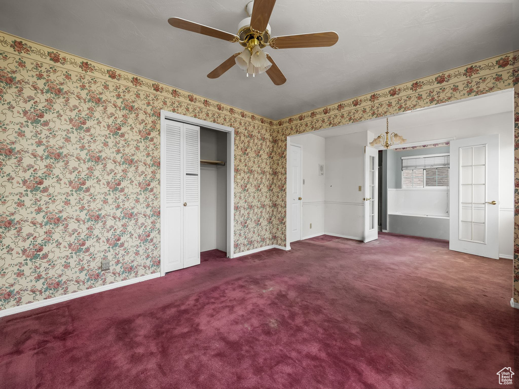 Unfurnished bedroom with carpet, wallpapered walls, ceiling fan, and a closet