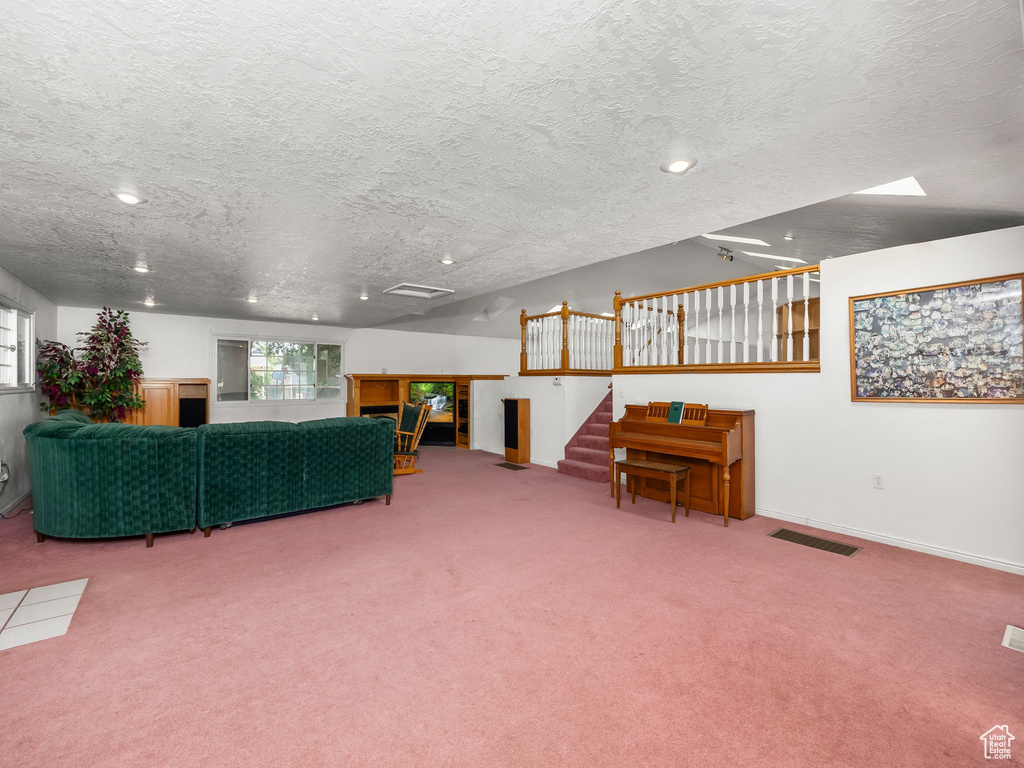 Carpeted living area with a textured ceiling, stairway, and recessed lighting