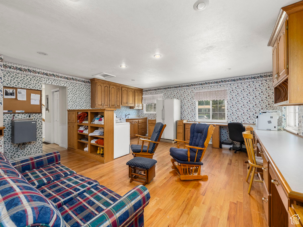 Living area featuring wallpapered walls, light wood finished floors, washer / clothes dryer, plenty of natural light, and built in study area