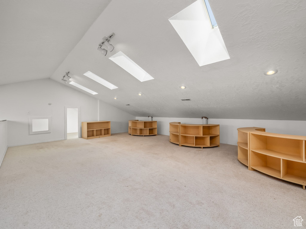 Additional living space featuring a skylight, lofted ceiling, carpet floors, and recessed lighting