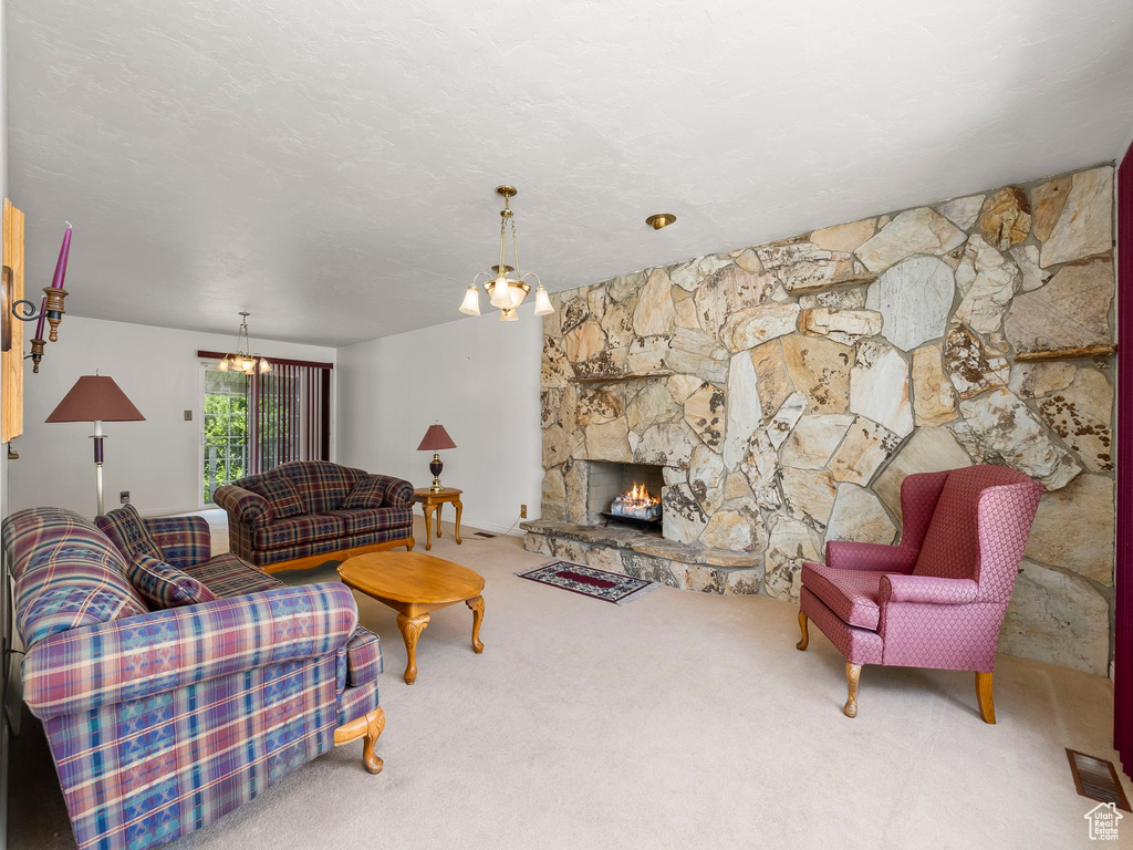Living area featuring a chandelier, carpet, and a stone fireplace