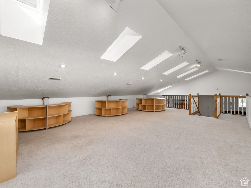 Bonus room featuring vaulted ceiling, a skylight, and carpet