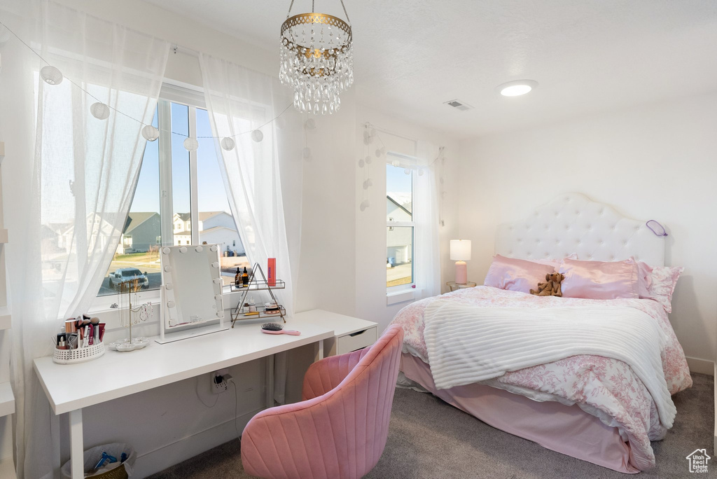 Carpeted bedroom with a chandelier and an office area