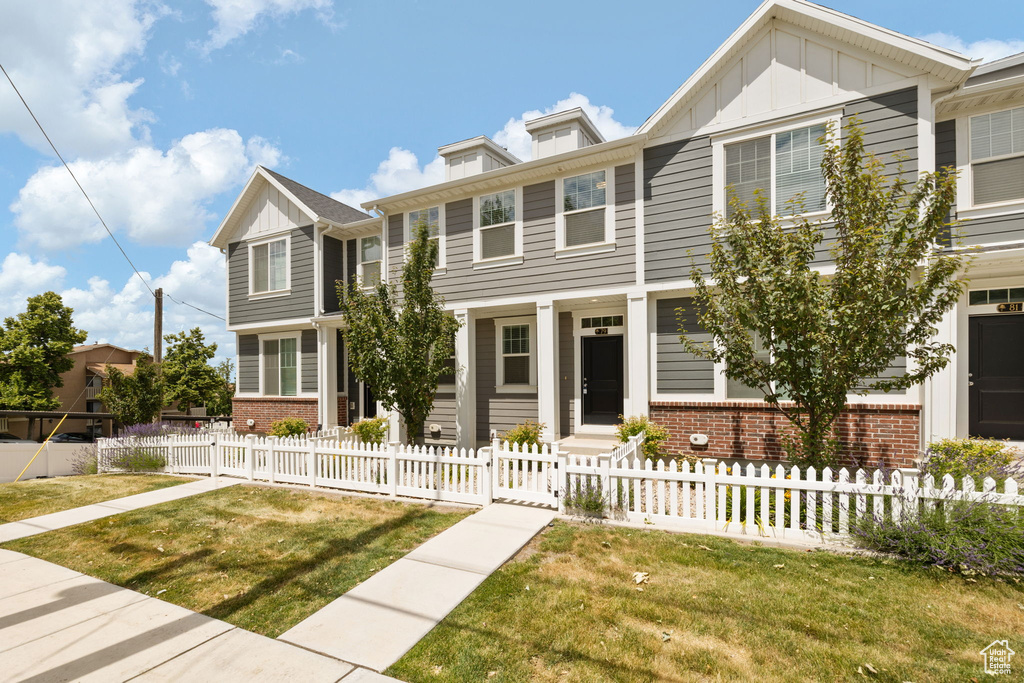 View of property with board and batten siding, brick siding, and a fenced front yard