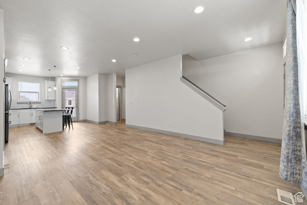 Living room with recessed lighting, light wood-type flooring, and stairway