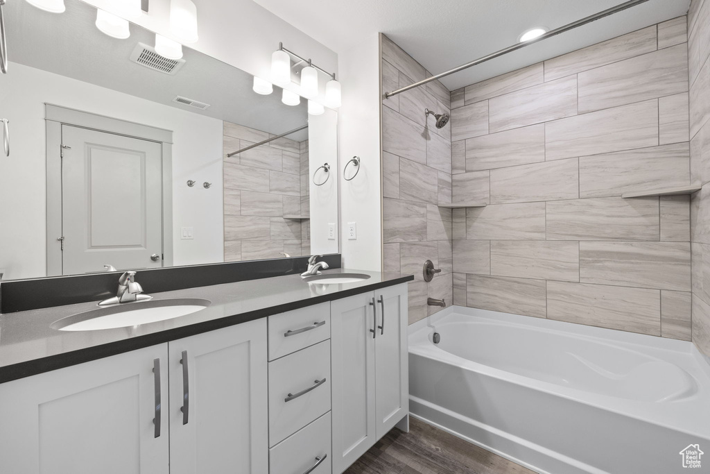 Bathroom with bathing tub / shower combination, double vanity, and wood finished floors
