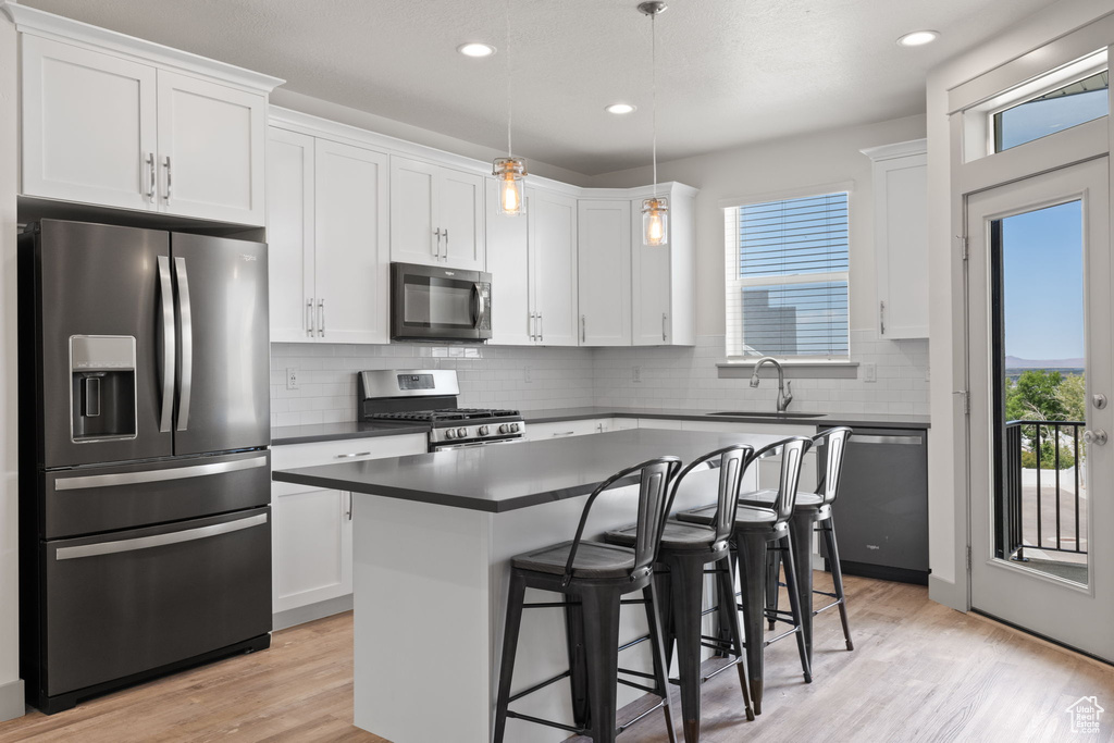 Kitchen with stainless steel appliances, dark countertops, plenty of natural light, white cabinetry, and recessed lighting