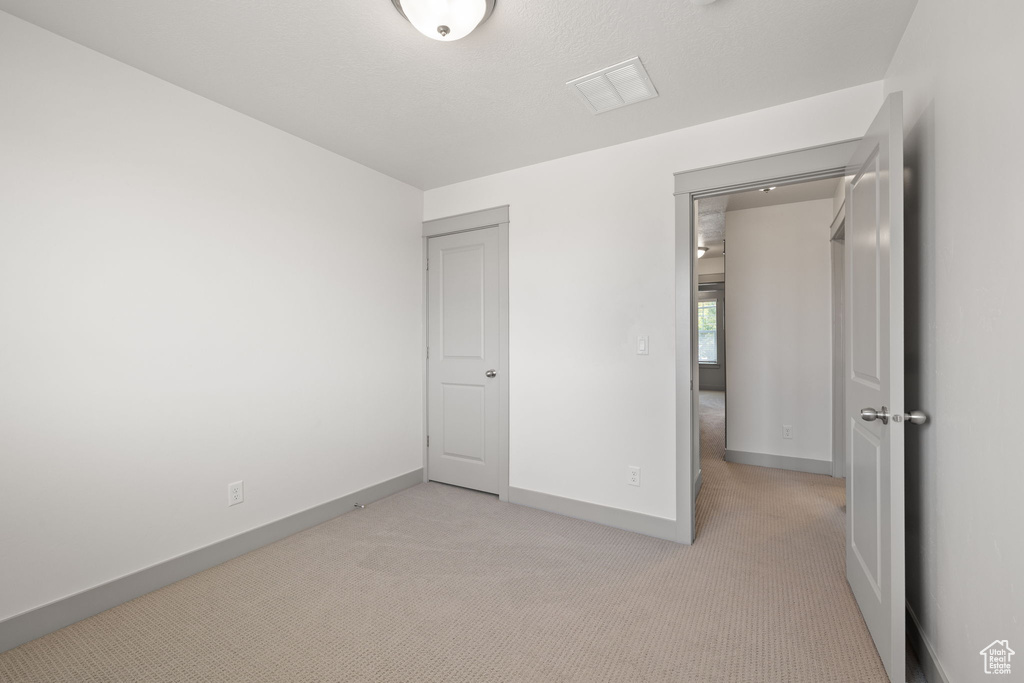 Unfurnished bedroom featuring light carpet and baseboards