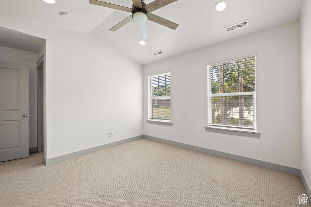Empty room featuring light colored carpet, ceiling fan, vaulted ceiling, and recessed lighting