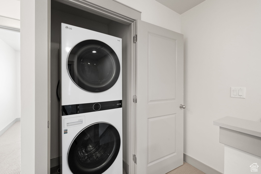 Laundry room featuring estacked washer and dryer and light carpet