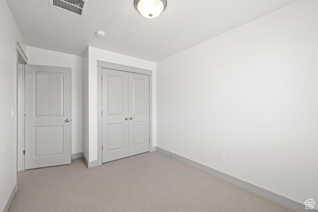 Unfurnished bedroom with light colored carpet and a closet