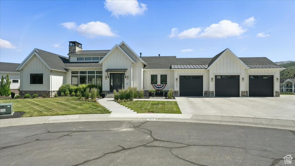 Modern inspired farmhouse with board and batten siding, driveway, and a standing seam roof