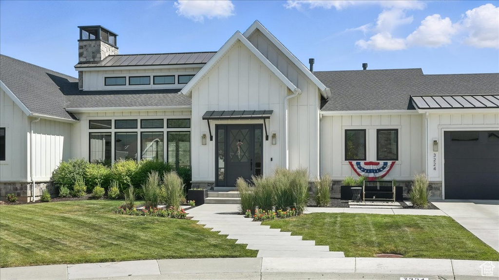 Modern inspired farmhouse featuring board and batten siding, a standing seam roof, and a metal roof