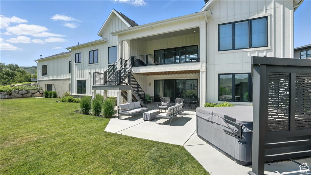 Rear view of house featuring board and batten siding, a patio, a yard, an outdoor living space, and stairway