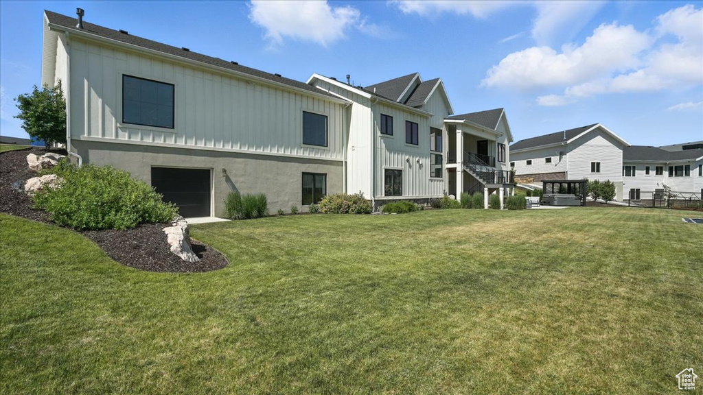 Back of property featuring board and batten siding, a residential view, and a yard