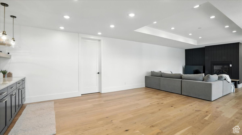 Living area featuring light wood-style floors, recessed lighting, a tray ceiling, and a fireplace