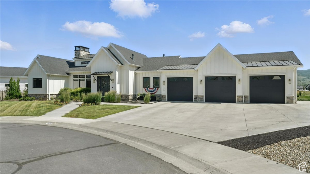 Modern inspired farmhouse featuring a standing seam roof, a garage, and board and batten siding