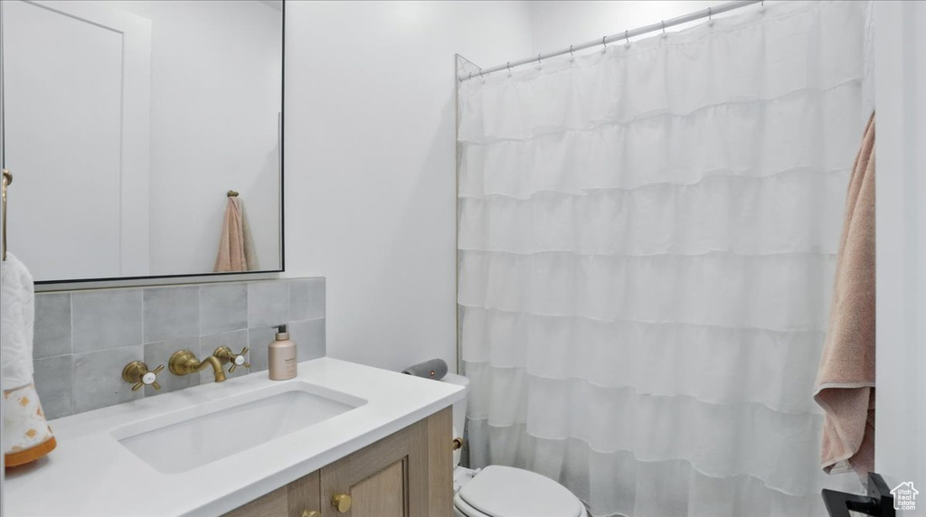 Bathroom featuring decorative backsplash, vanity, and curtained shower