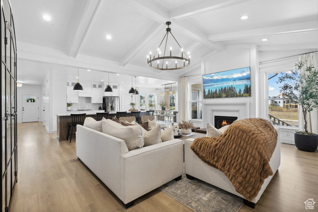 Living area with a chandelier, a lit fireplace, light wood-style flooring, and recessed lighting