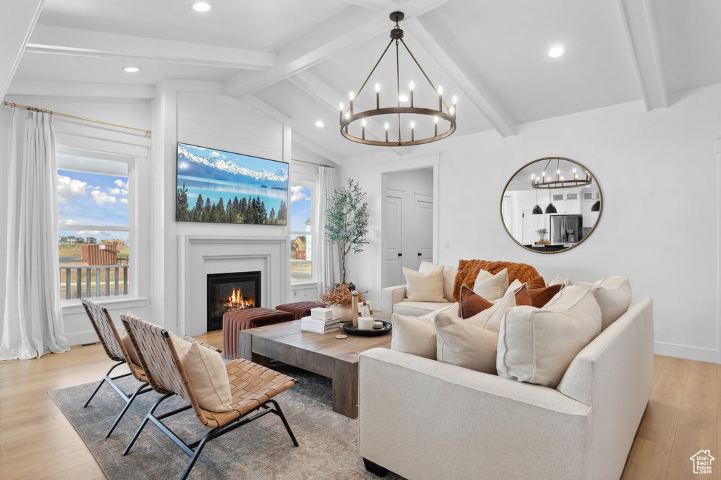 Living area with a chandelier, light wood-style flooring, a glass covered fireplace, and recessed lighting