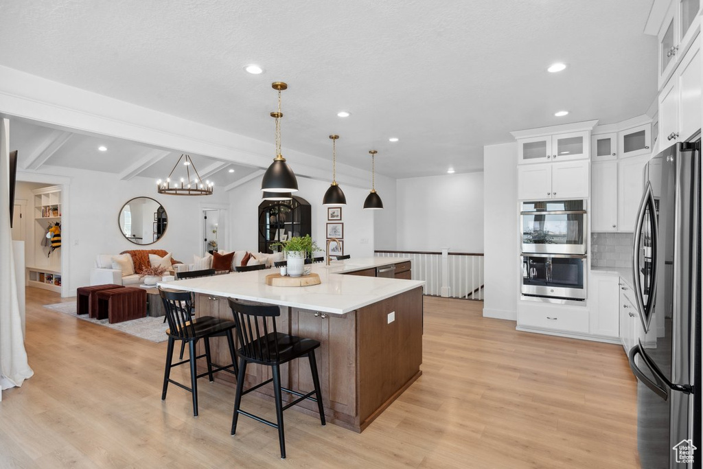 Kitchen with appliances with stainless steel finishes, open floor plan, recessed lighting, decorative backsplash, and light wood-type flooring