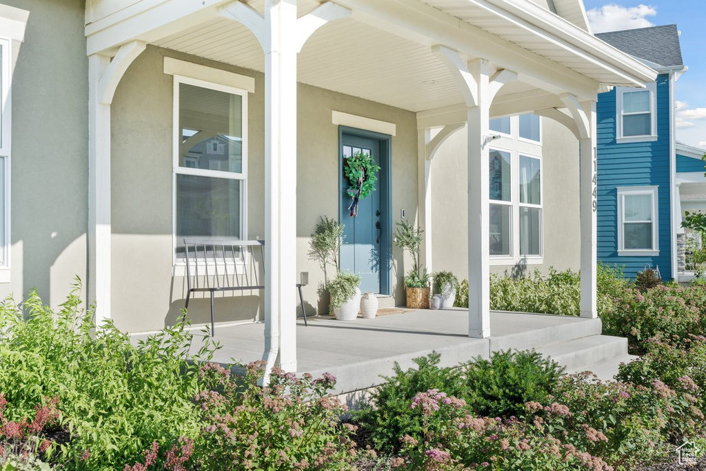 View of exterior entry with covered porch and stucco siding