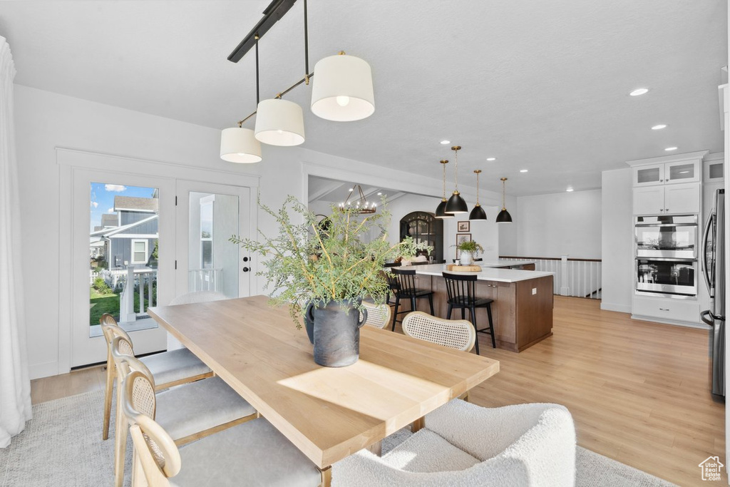 Dining area with light wood-style flooring, recessed lighting, and a chandelier