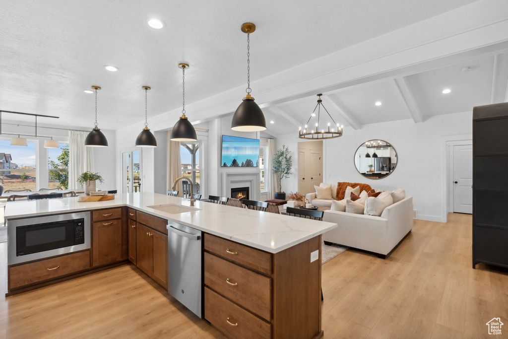 Kitchen with stainless steel appliances, open floor plan, light wood-style flooring, recessed lighting, and brown cabinetry