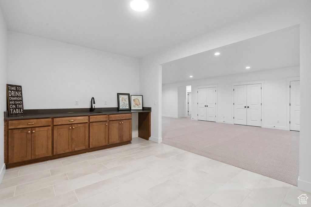 Kitchen with dark countertops, brown cabinetry, light carpet, and recessed lighting