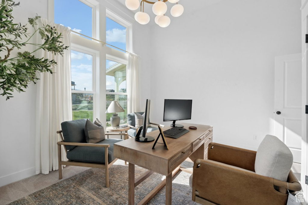 Home office with a towering ceiling, carpet floors, and a chandelier