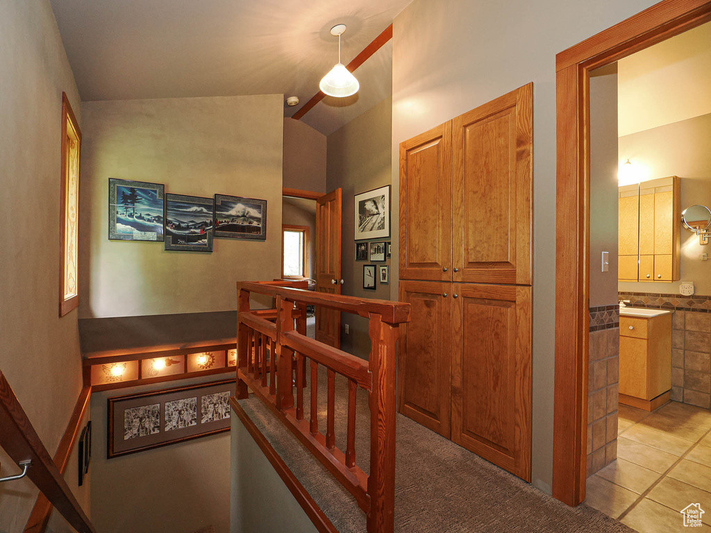 Hallway featuring vaulted ceiling and light tile patterned flooring