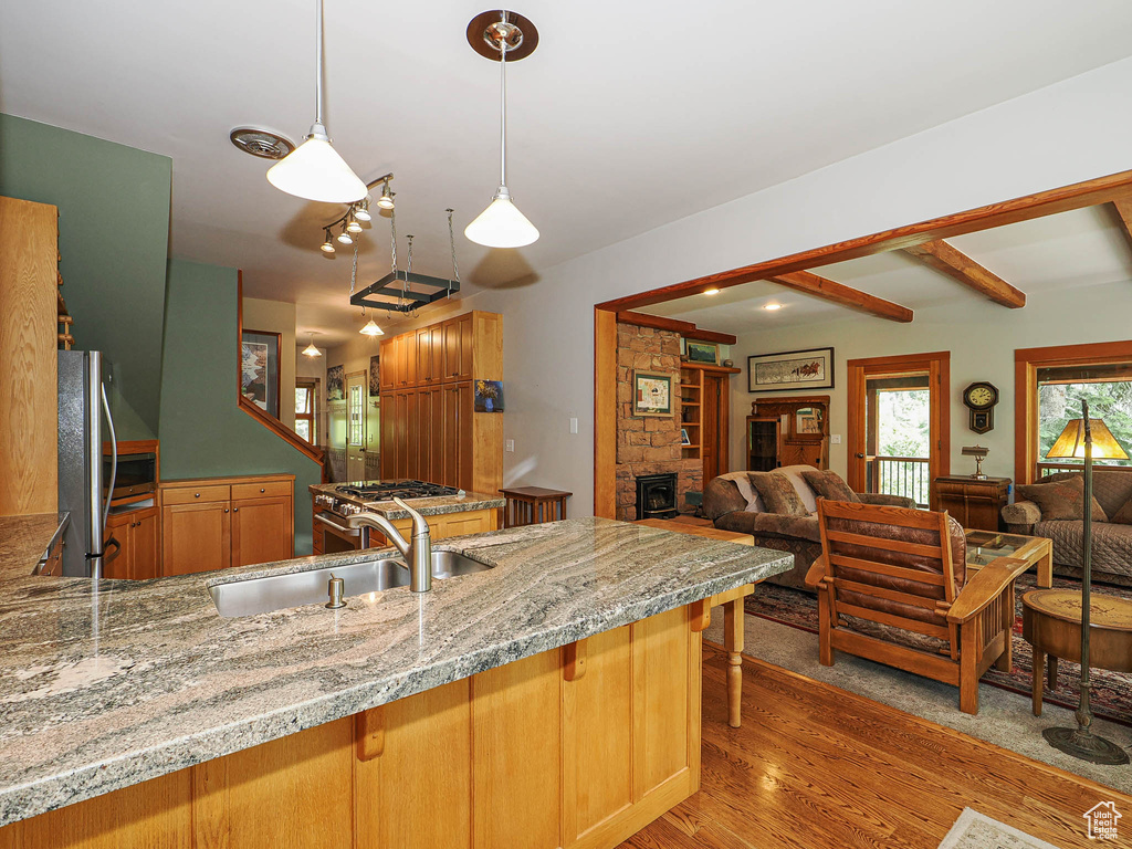 Kitchen with freestanding refrigerator, open floor plan, light wood-style floors, a peninsula, and light stone countertops