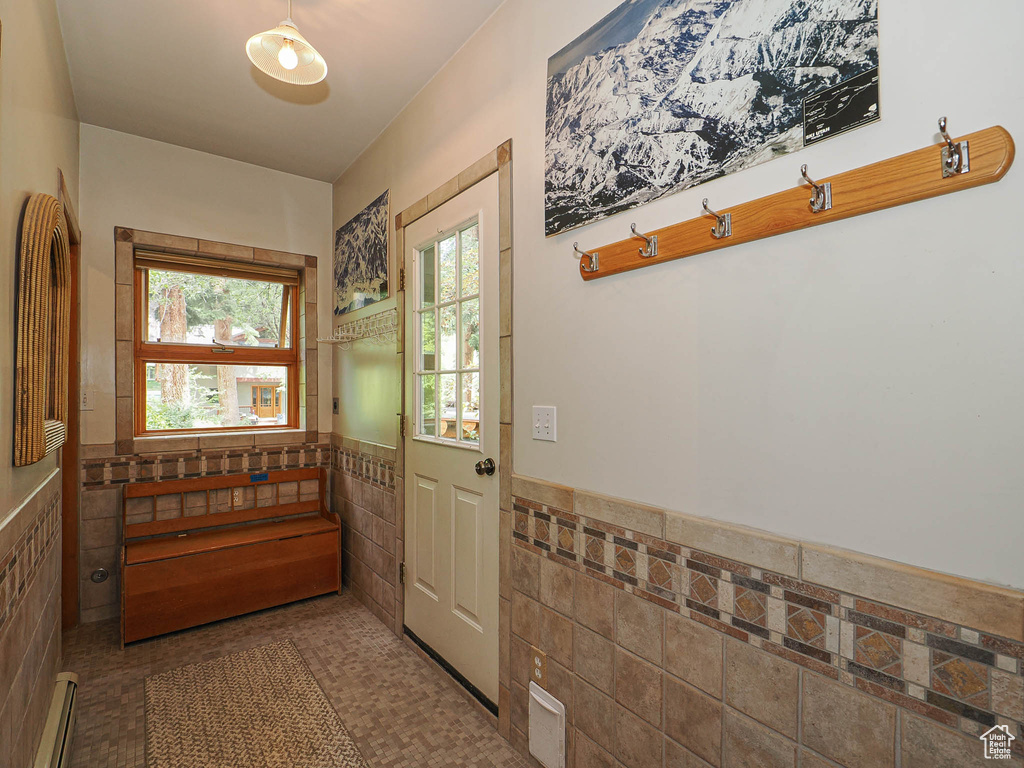 Doorway to outside featuring tile walls, wainscoting, and a baseboard radiator
