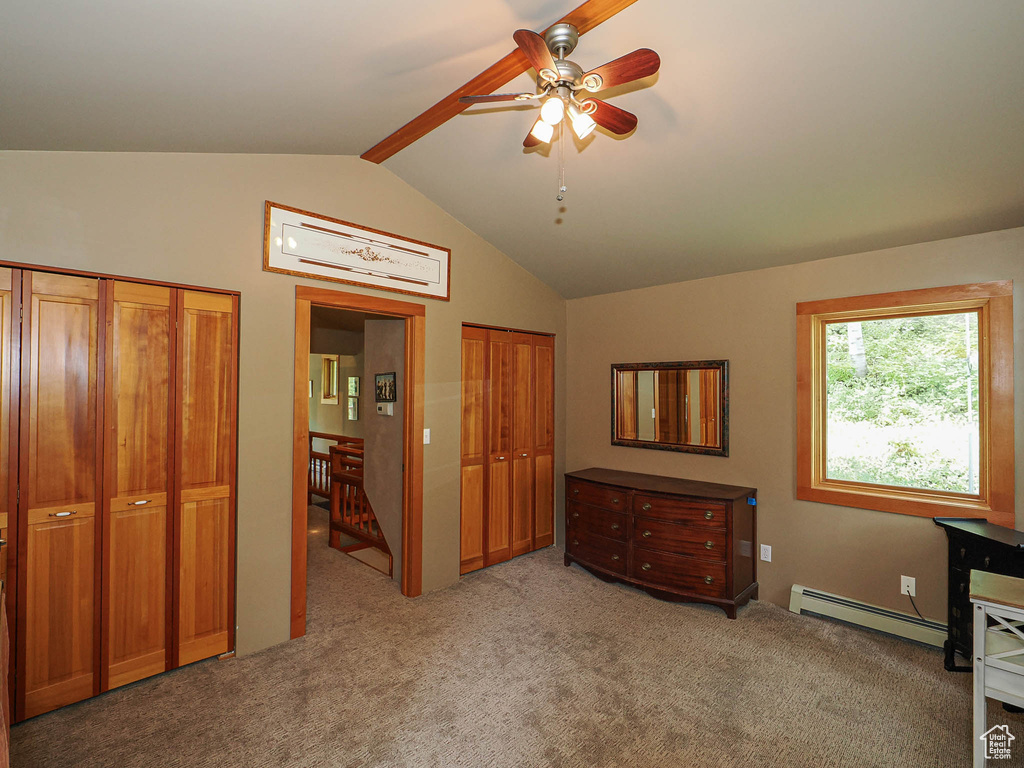 Bedroom with a baseboard heating unit, two closets, light colored carpet, and ceiling fan
