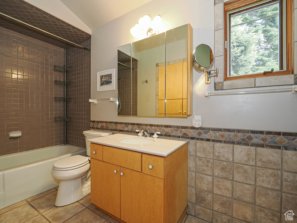 Full bathroom with vanity, bathing tub / shower combination, tile walls, tile patterned flooring, and wainscoting