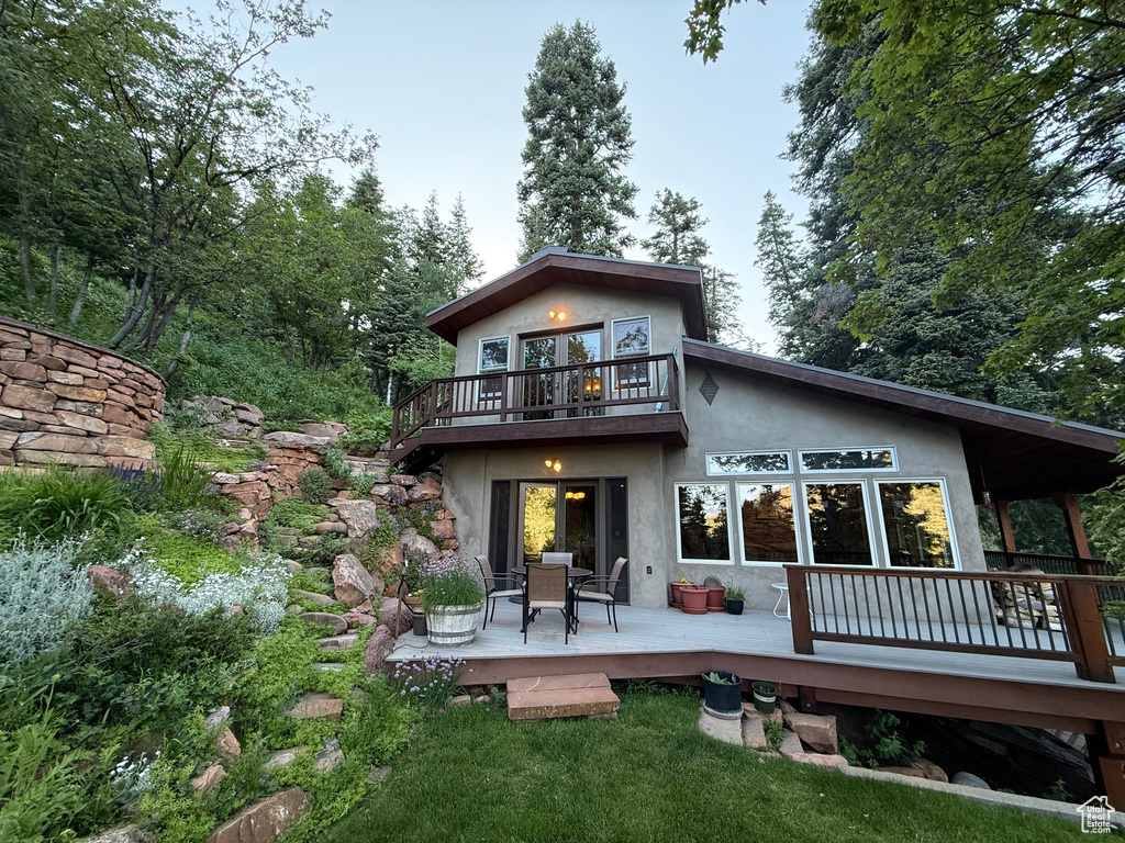 Back of house featuring stucco siding, a wooden deck, and a balcony