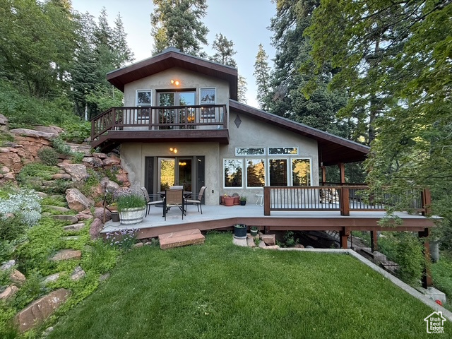 Rear view of house featuring stucco siding, a yard, and a wooden deck
