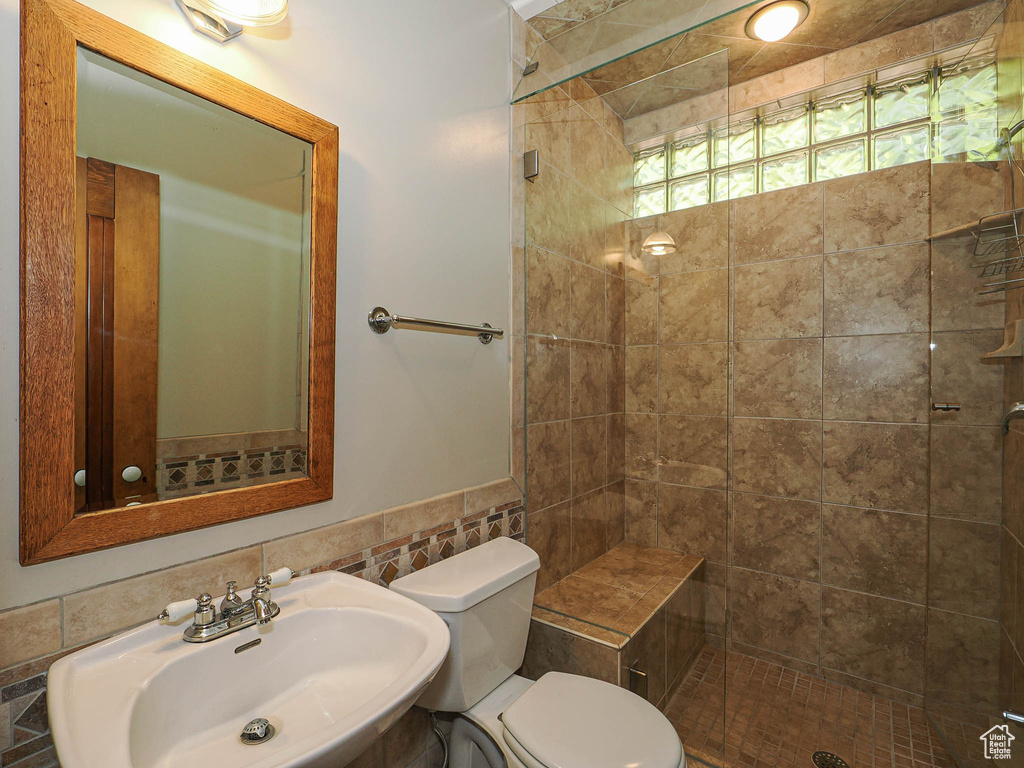Bathroom featuring a shower stall and tile walls