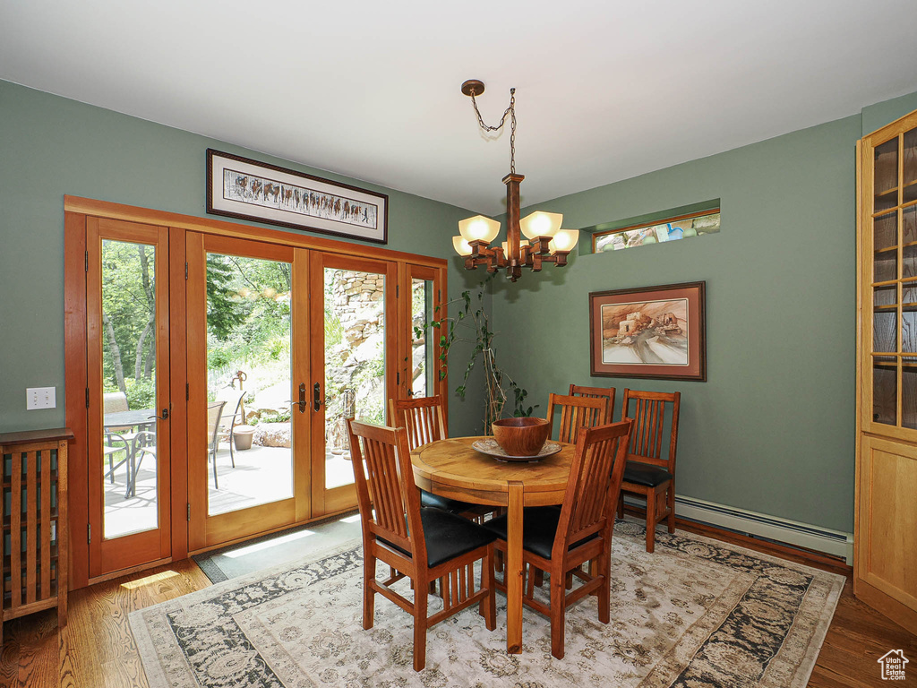 Dining room with a baseboard radiator, a chandelier, french doors, and wood finished floors