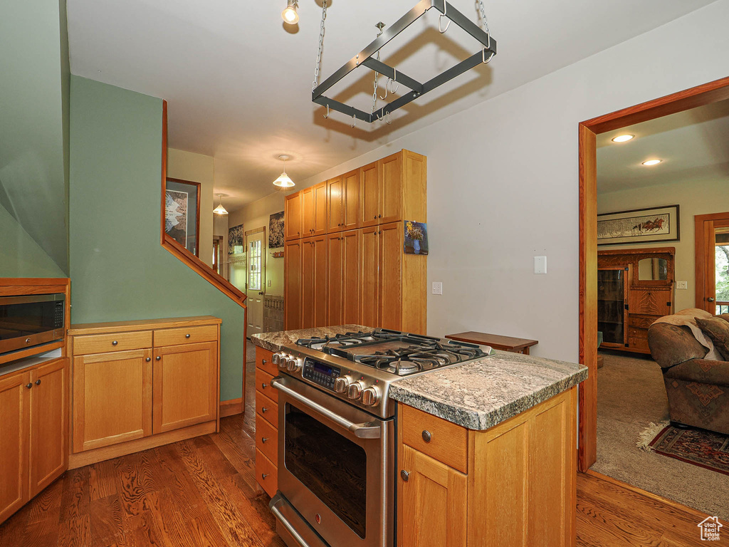 Kitchen with stainless steel appliances, dark wood finished floors, a chandelier, a center island, and light countertops