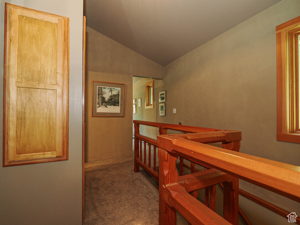 Corridor with an upstairs landing, carpet flooring, and lofted ceiling