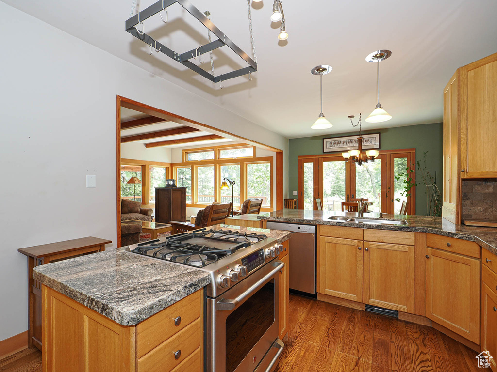 Kitchen with appliances with stainless steel finishes, a chandelier, dark wood-style flooring, a peninsula, and beamed ceiling